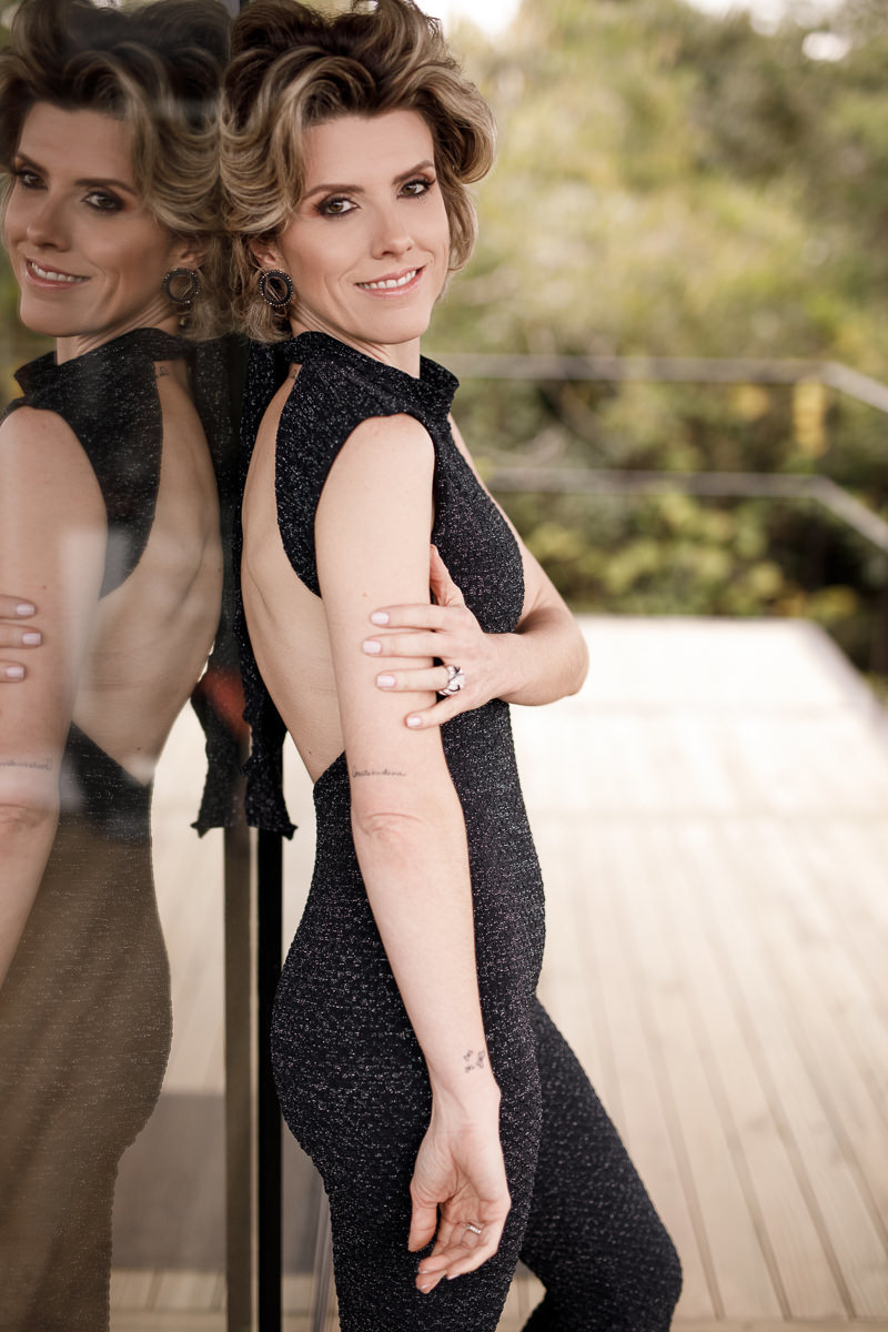 Modelo Ana Paula encostada no vidro da sacada com um leve reflexo do vidro no lado esquerdo da foto