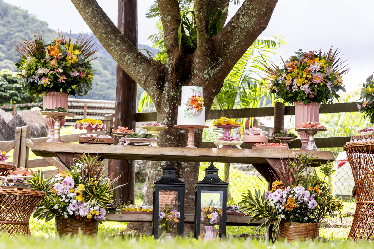 mesa de festa de debutante com bolo e arranjos florais.