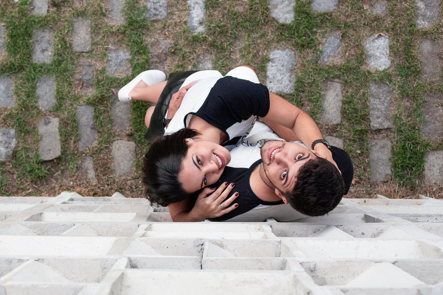 casal sorrindo e abraçado em ensaio pre wedding, visto de cima em meio a blocos de concreto e grama no Rio.