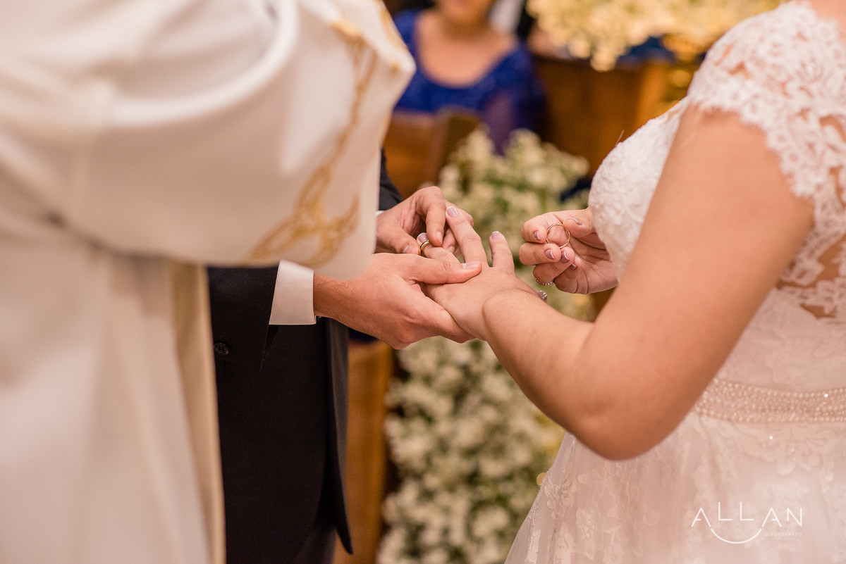 Noivo colocando aliança na mão da noiva