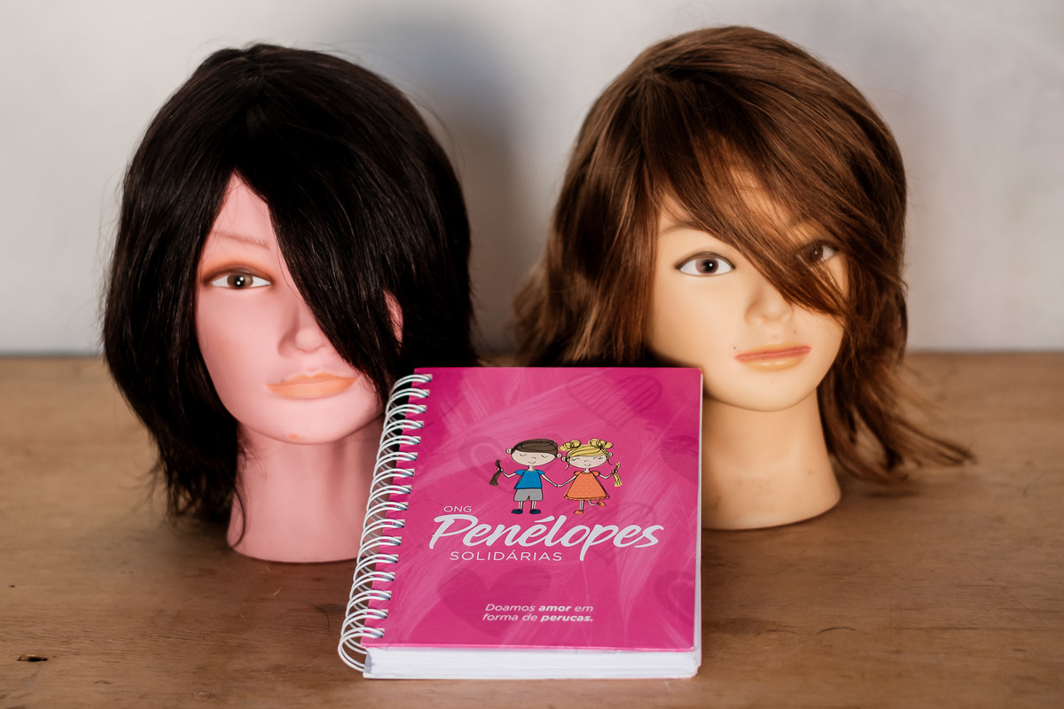 dois bustos com peruca loira e morena e agenda Penelopes Solidárias