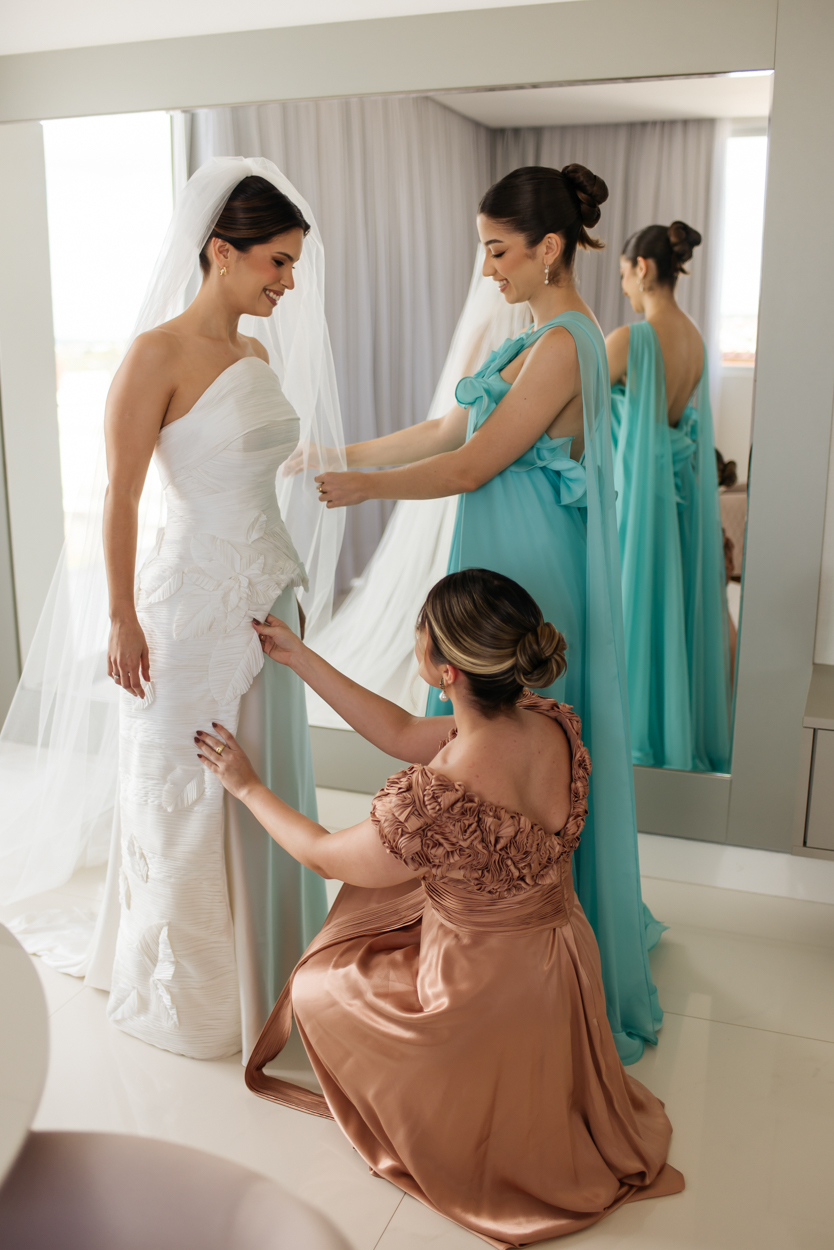 Madrinha ajudando a noiva a ajustar o vestido