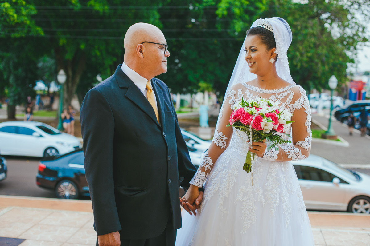 A Mayara, vestida de noiva, na porta da igreja, momentos antes da entrada na paróquia para seu casamento.