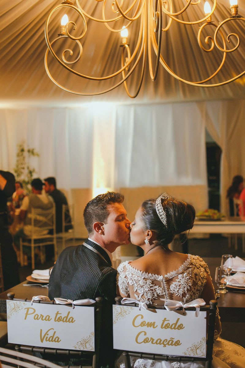 beijo dos noivos, cadeira enfeitada com plaquinha com texto do casal, tudo muito romantico.