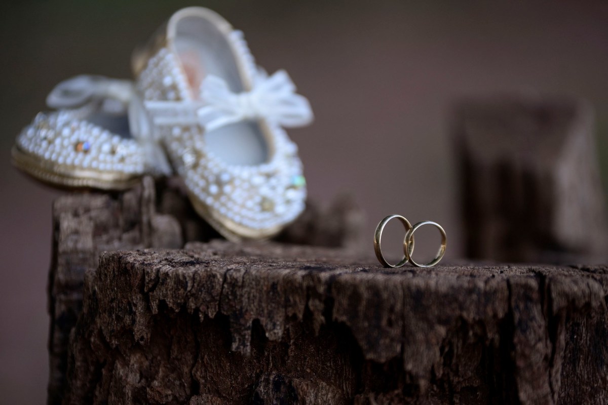 detalhe em foto de gestante das alianças do pais e do sapato da Bebê. Fotografia André Monteiro