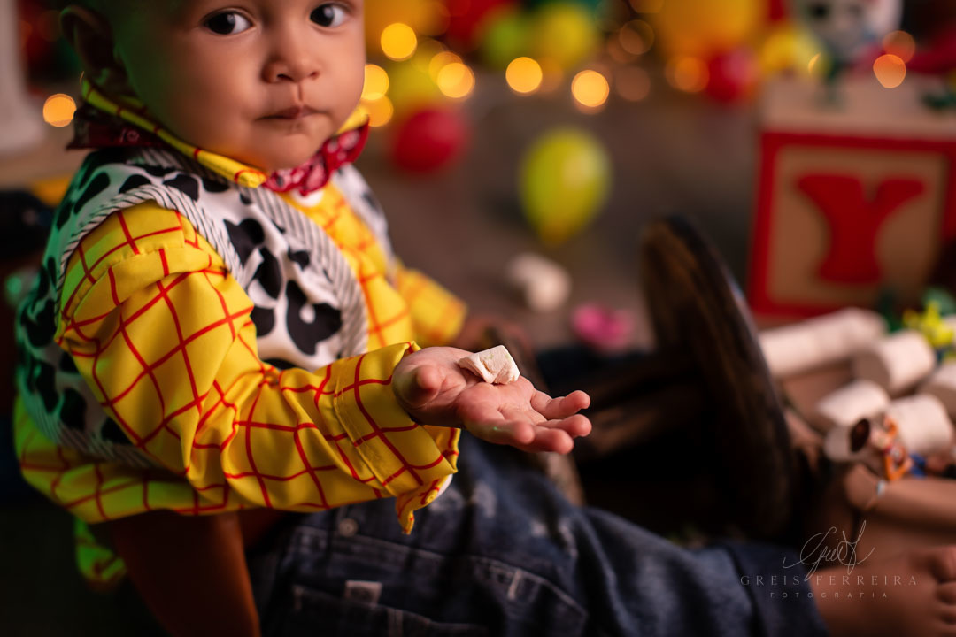 smash the cake toy story ensaio de aniversario de bebe de 1 ano vestido de woody segurando um pedao do bolo