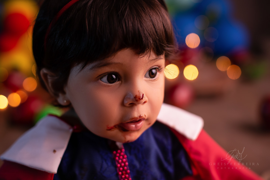 retrato de rosto bebe de 1 ano olhando para a direita com o rosto sujo de chocolate e fundo com bokeh