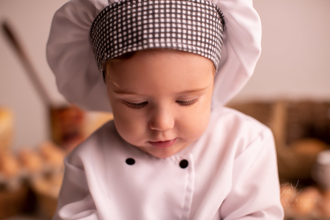ensaio de bebe de 9 meses de padaria com roupa de chef de cozinha  olhando para baixo