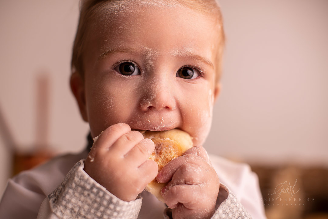 ensaio de bebe 9 meses padeiro com paes em cestos colheres de pau bule de cafe ovos e bebe com roupa de chef de cozinha  mordendo um pao