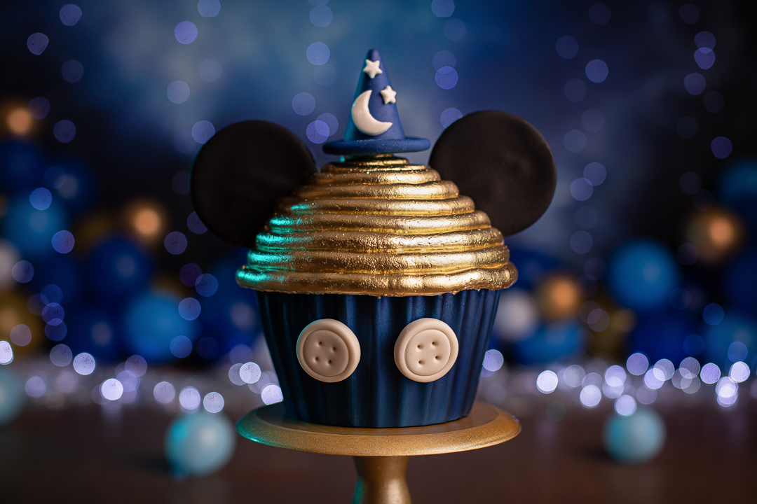 Smash the cake mickey ensaio de bebe com bolo de chapeu de feiticeiro com orelhas do mickey com  com fundo azul piscas e baloes desfocado