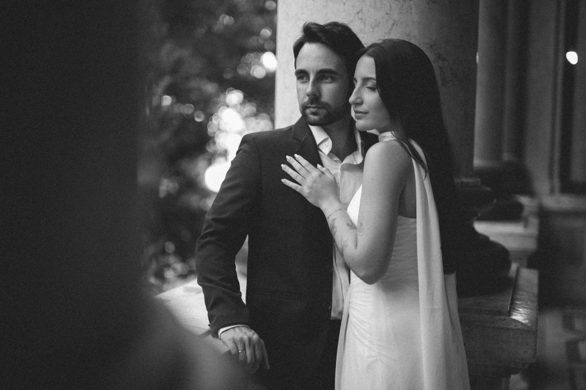 Casal abraçado em uma das colunas externas em foto preta e branca, evidenciando o estilo sofisticado deste ensaio de casamento no Rio de Janeiro.