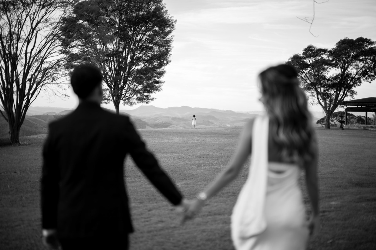 Casal de mãos dadas diante da paisagem e das árvores do Vale dos Desejos.