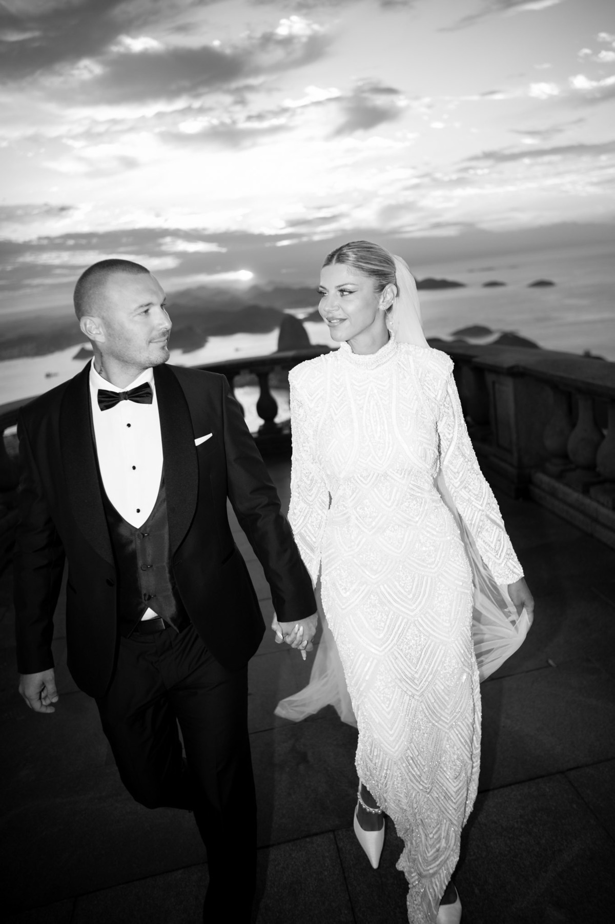 casal de noivos elegantes caminham se olhando enquanto sao fotografados por douglas felicio no cristo redentor