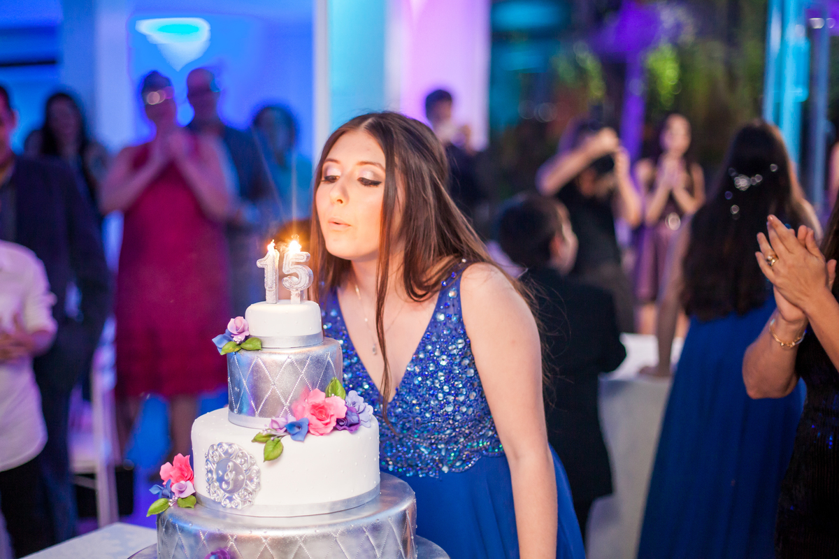 jovem apagando a vela sob o bolo em festa de 15 anos