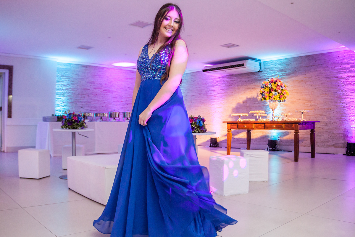 jovem de vestido azul balançando a saia do vestido em festa de 15 anos