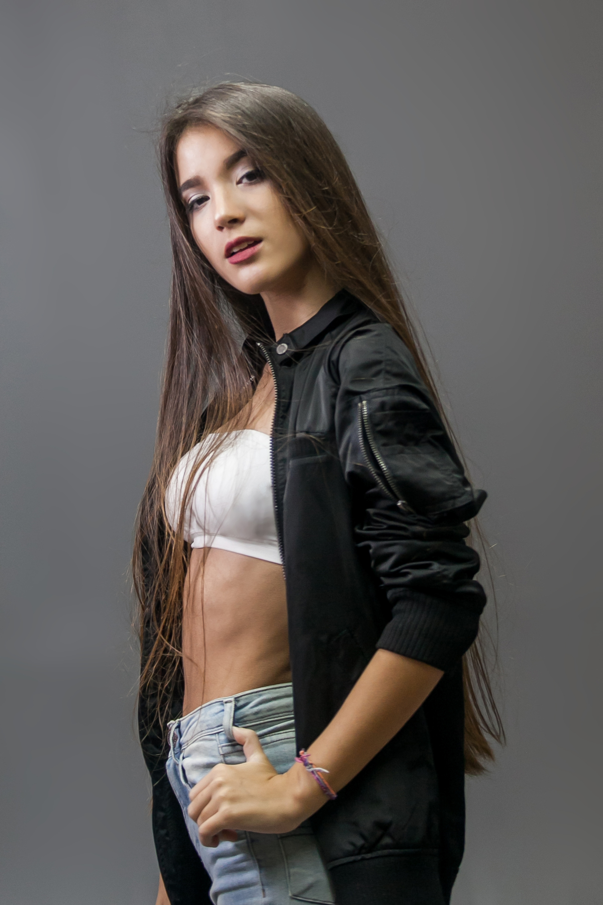 menina em fot ode perfil vestindo top branco e jaqueta preta