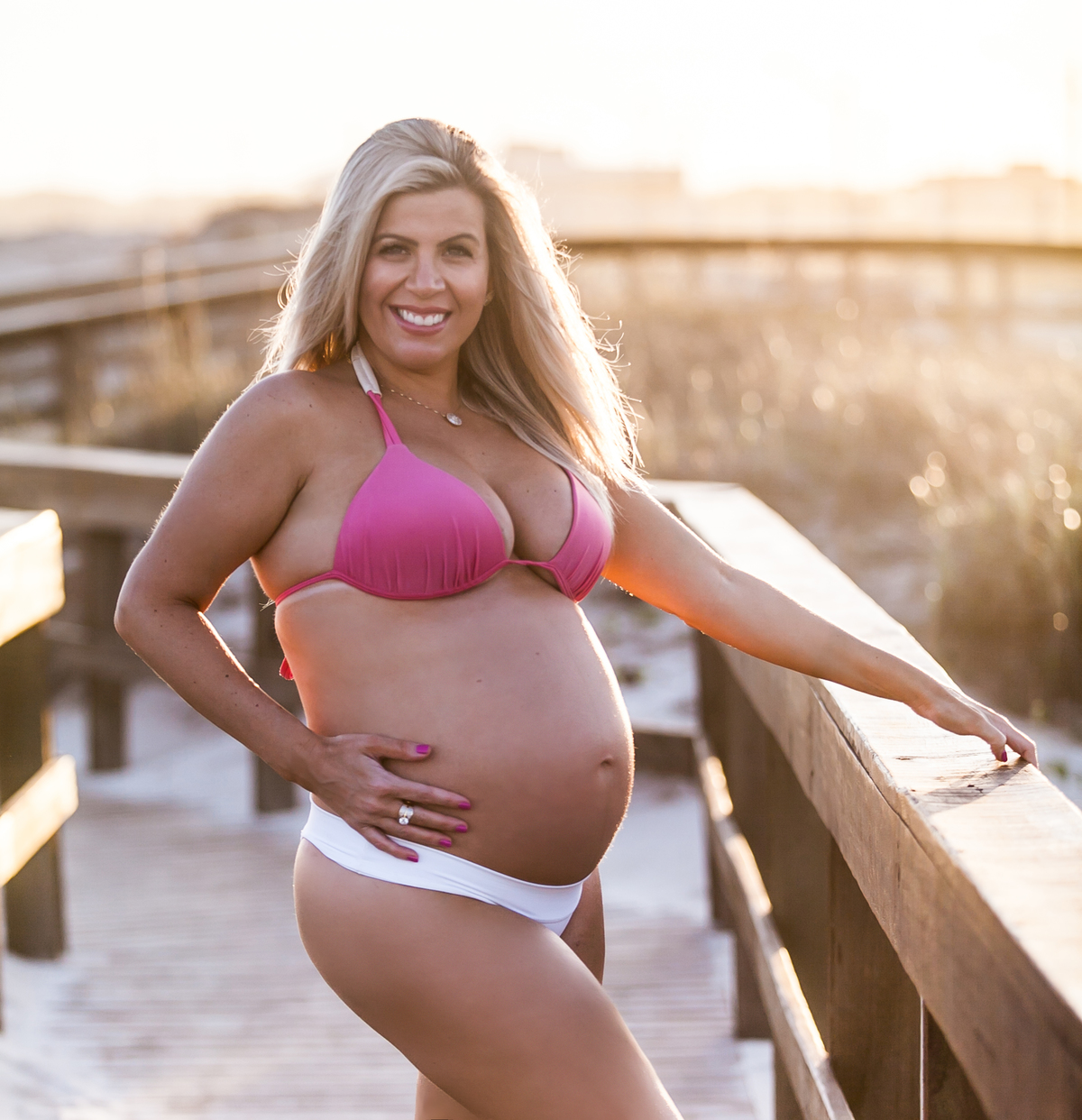 gestante sendo fotografada ao pôr do sol