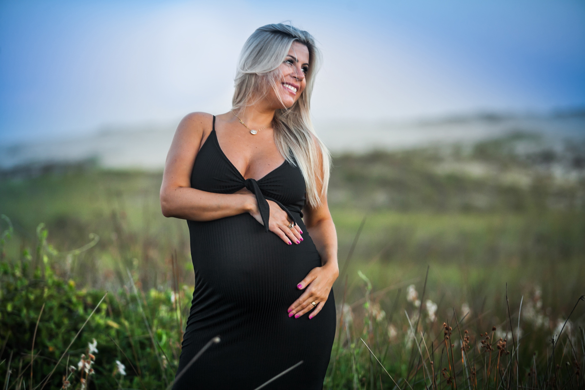 gestante de vestido preto olhando para o lado 