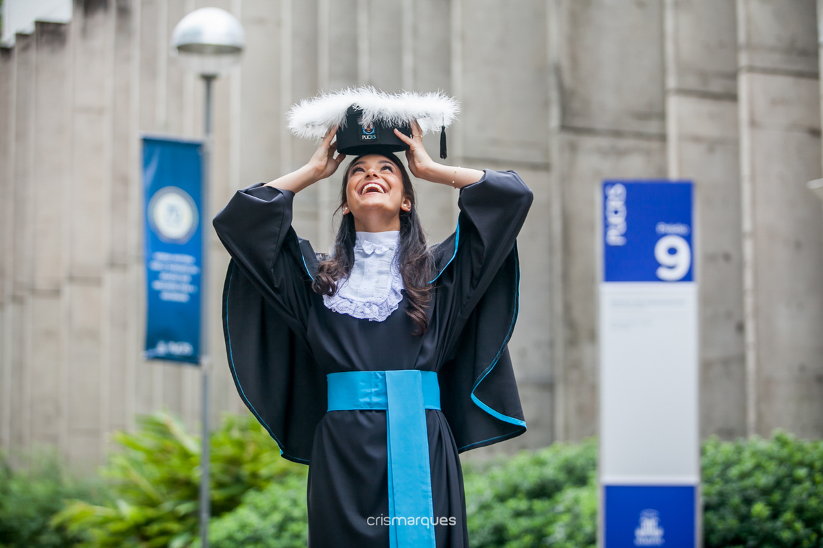 formanda segurando o barrete acima da cabeça e olhando para cima