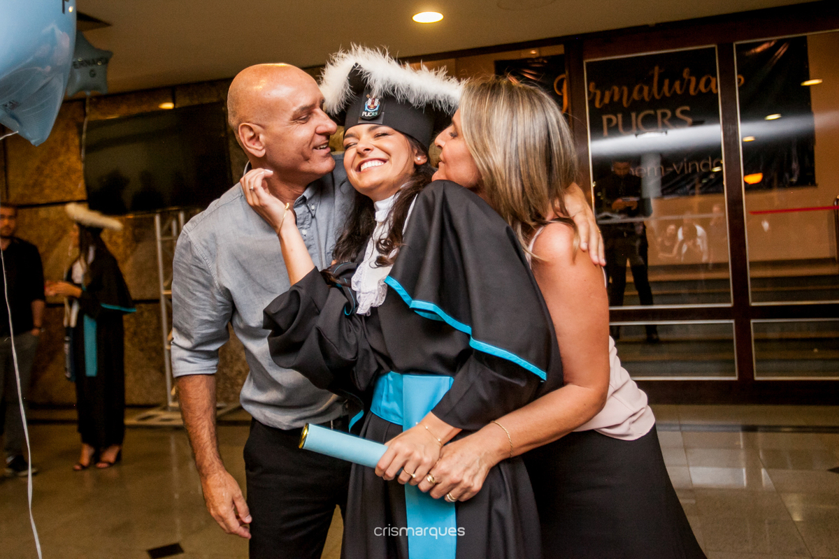 formanda recebendo beijo de seus pais na saída da formatura de arquitetura 