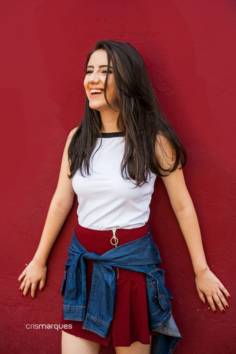 menina apoiada em parede vermelha