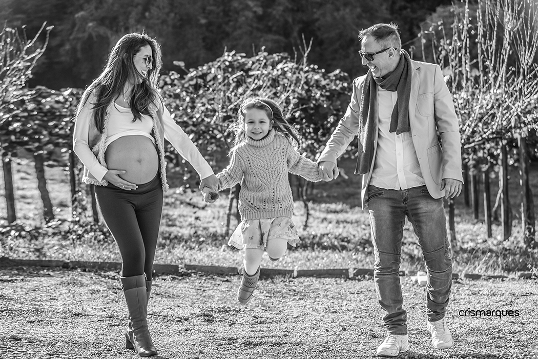 menina saltando de mãos dadas com os pais