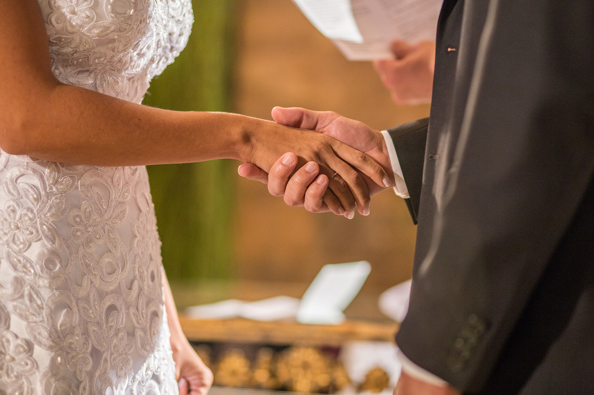 Detalhe do noivo segurando a mão da noiva na cerimônia do casamento