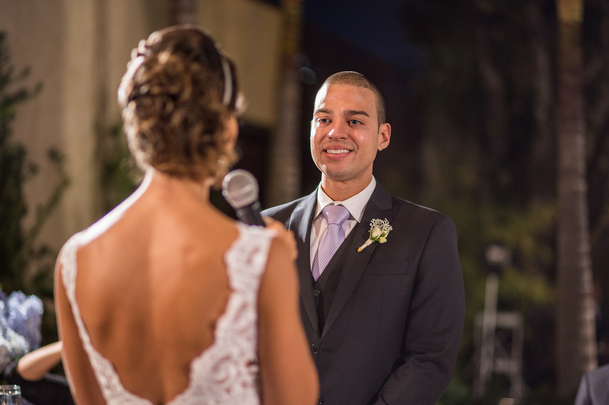 Noivo olhando para a noiva enquanto ela diz os votos na cerimônia do casamento