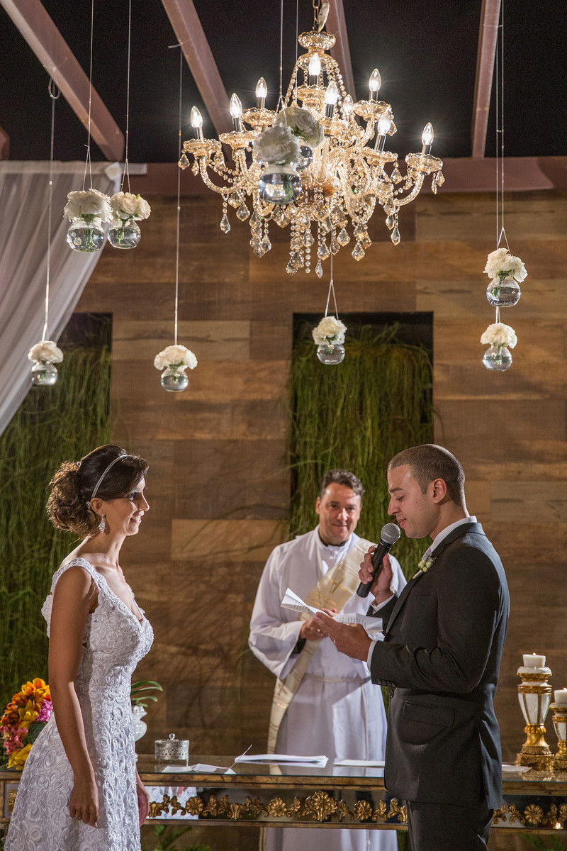 Noivos de frente enquanto o noivo diz os votos na cerimônia do casamento
