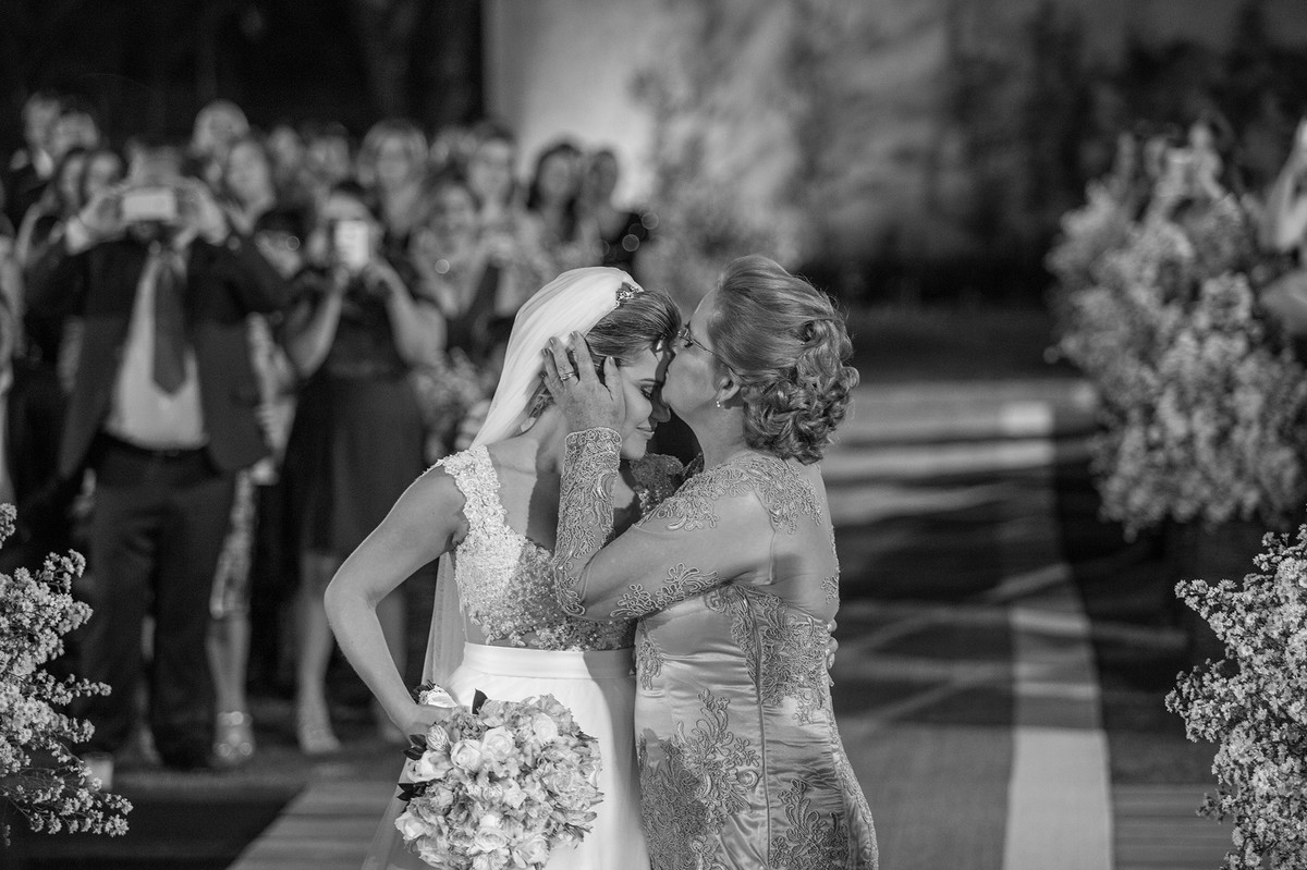 Mãe beijando a testa da noiva na cerimônia do casamento