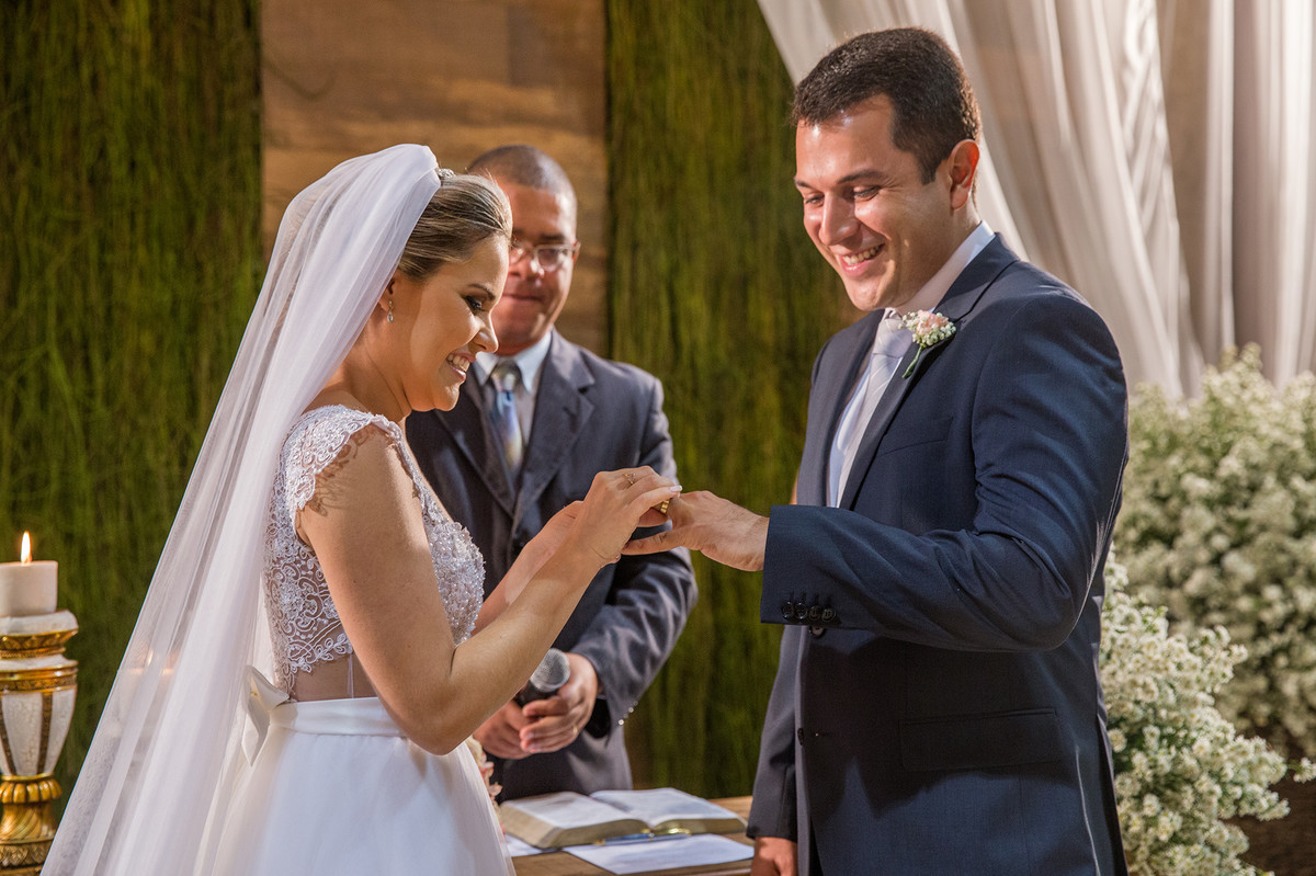 Noiva colocando a aliança na mão do noivo na cerimônia do casamento