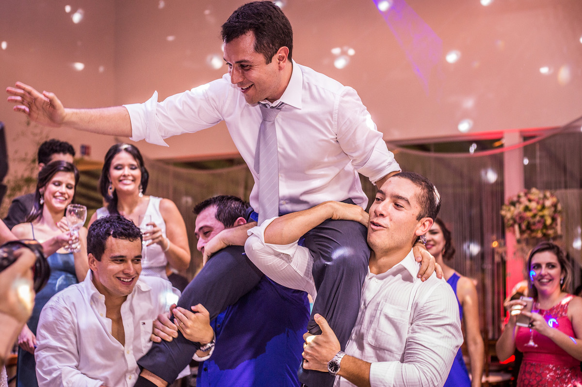 Amigos levantando o noivo na recepção do casamento