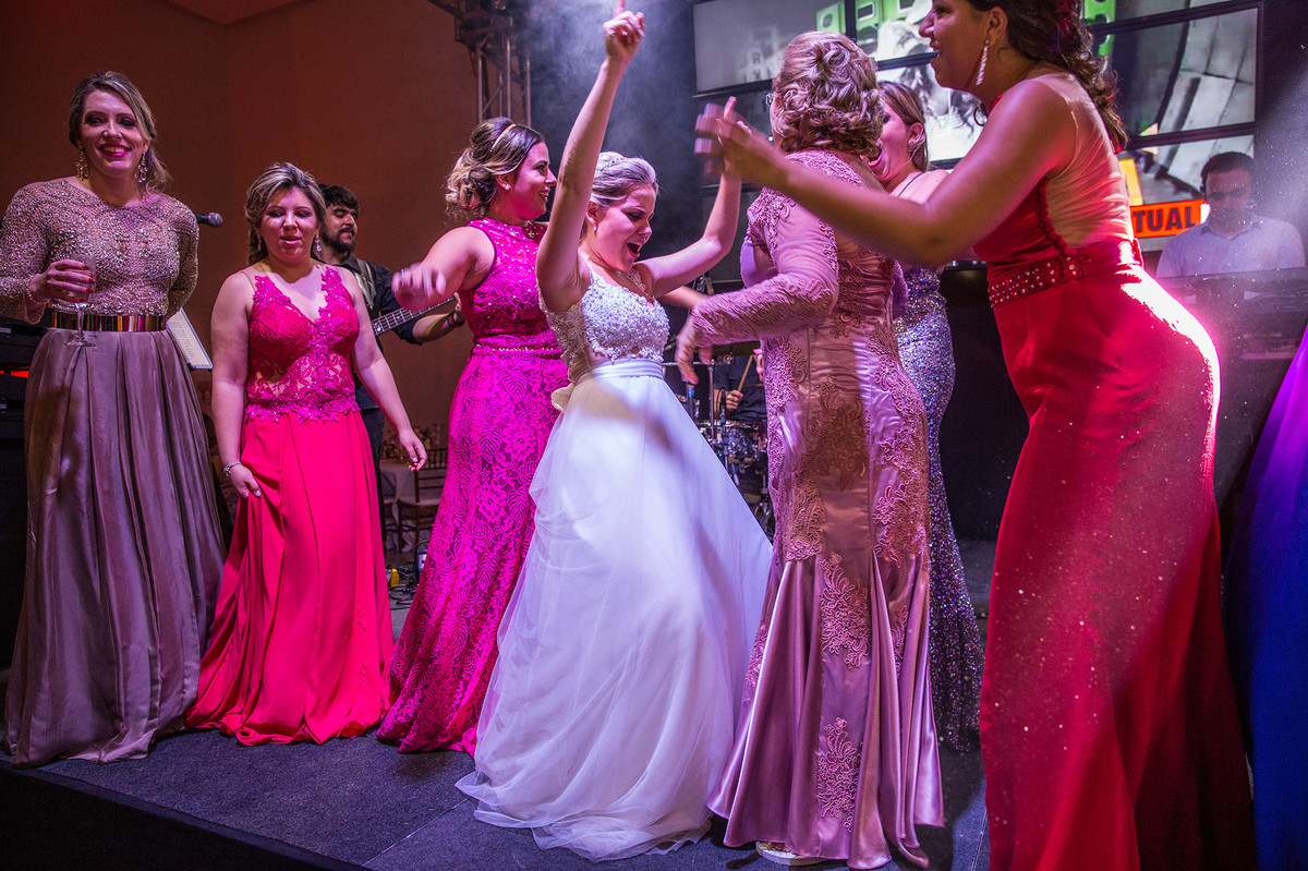 Noiva, madrinhas e mãe dançando no palco da banda na recepção do casamento