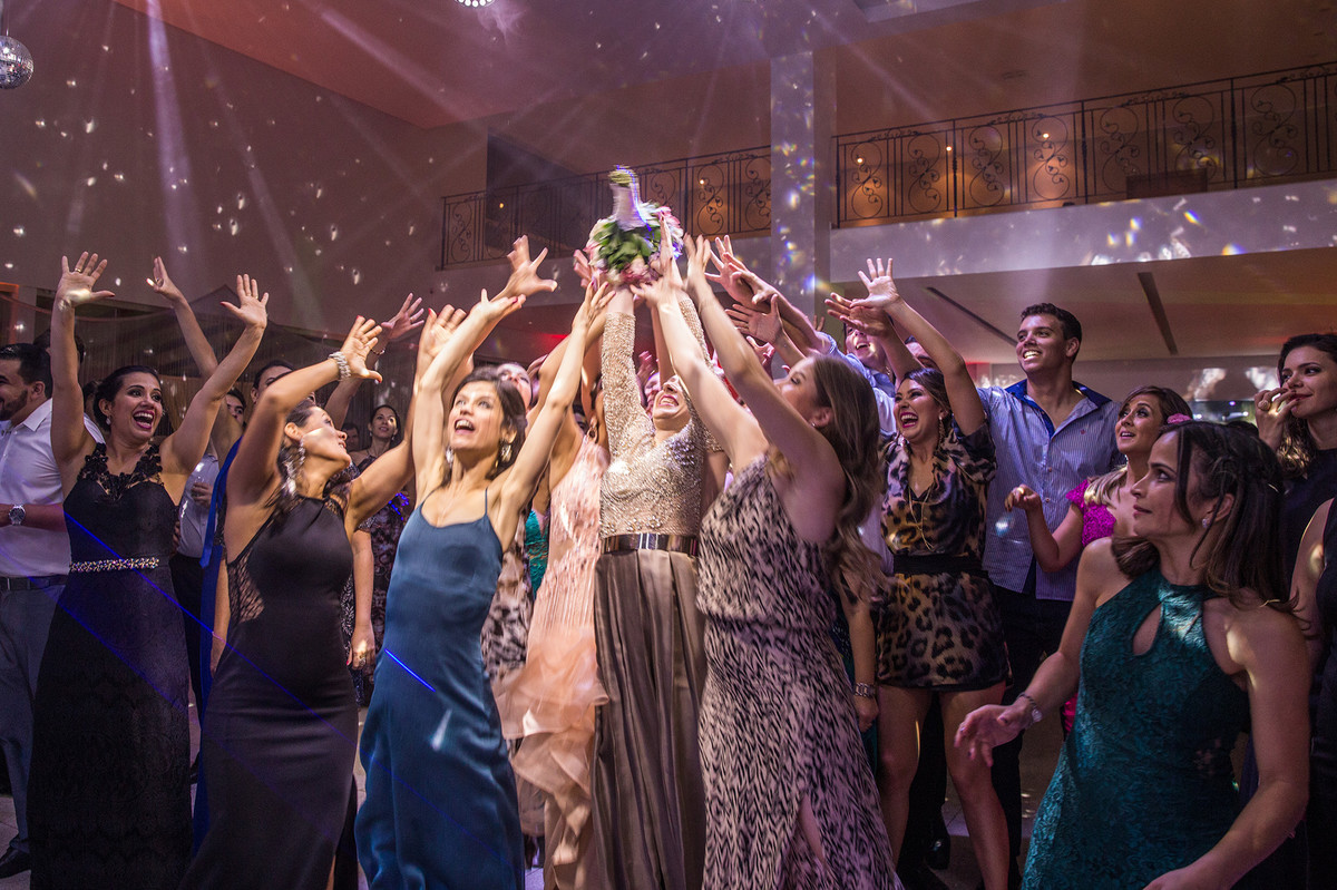 Solteiras tentando pegar o buquê da noiva na recepção do casamento