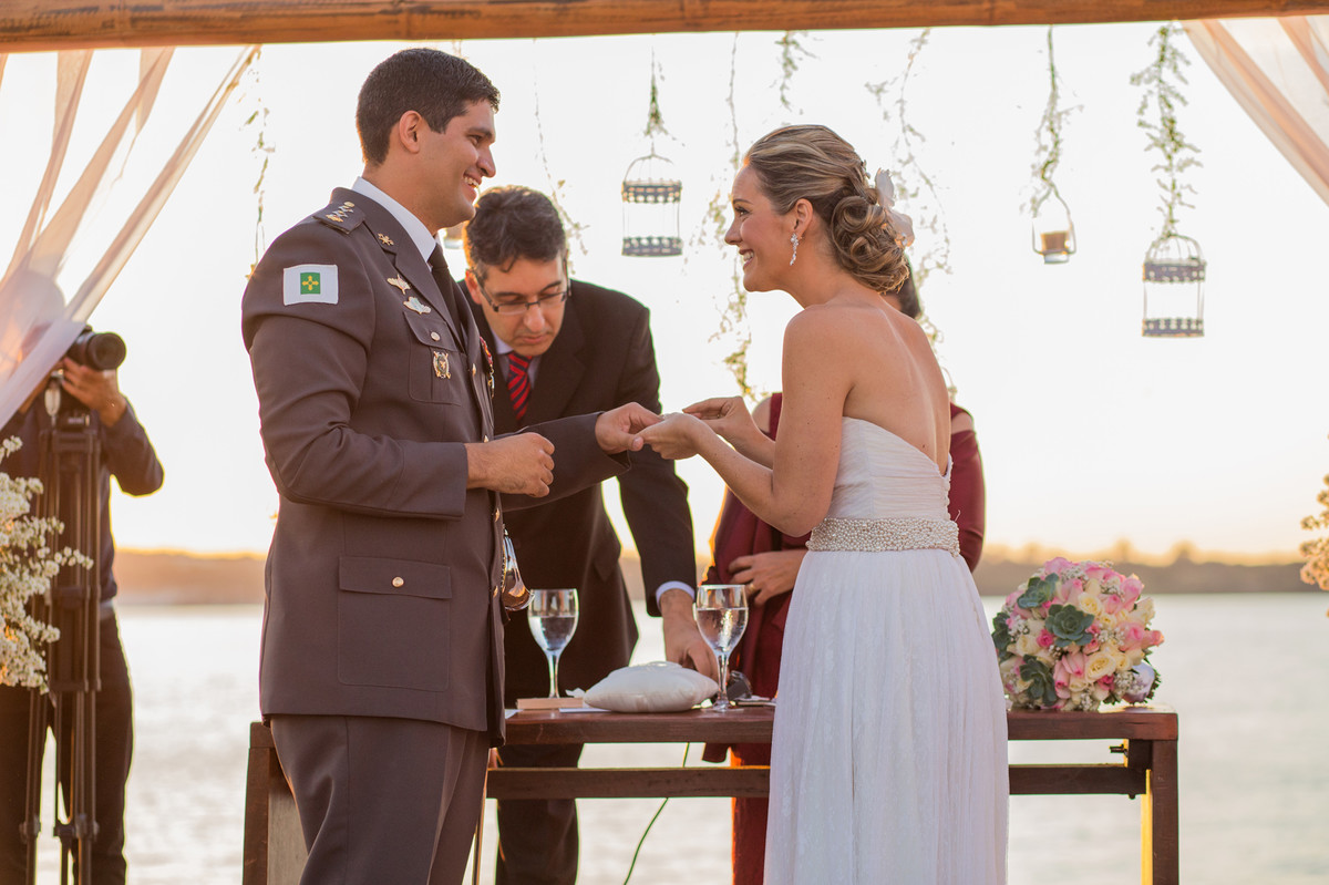 Noiva colocando a aliança na mão do noivo na cerimônia do casamento