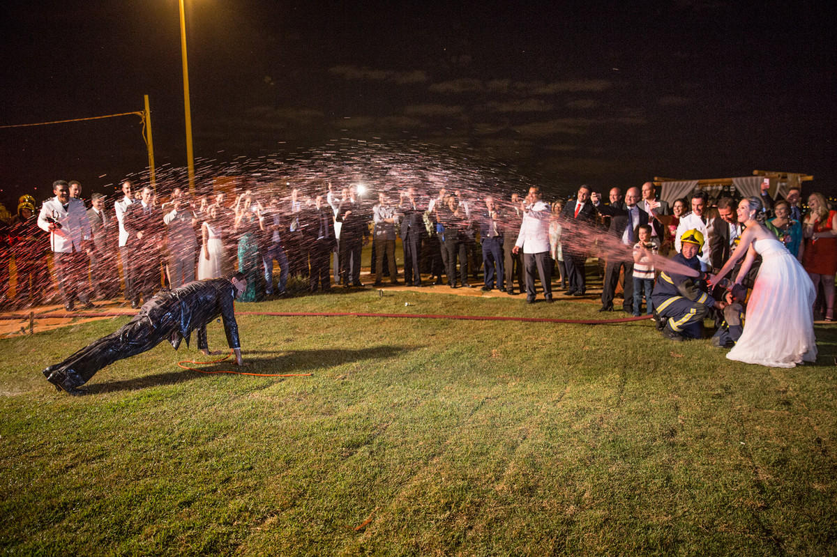 Noivo bombeiro leva banho de mangueira do caminhão dos bombeiros dado pela noiva na recepção do casamento