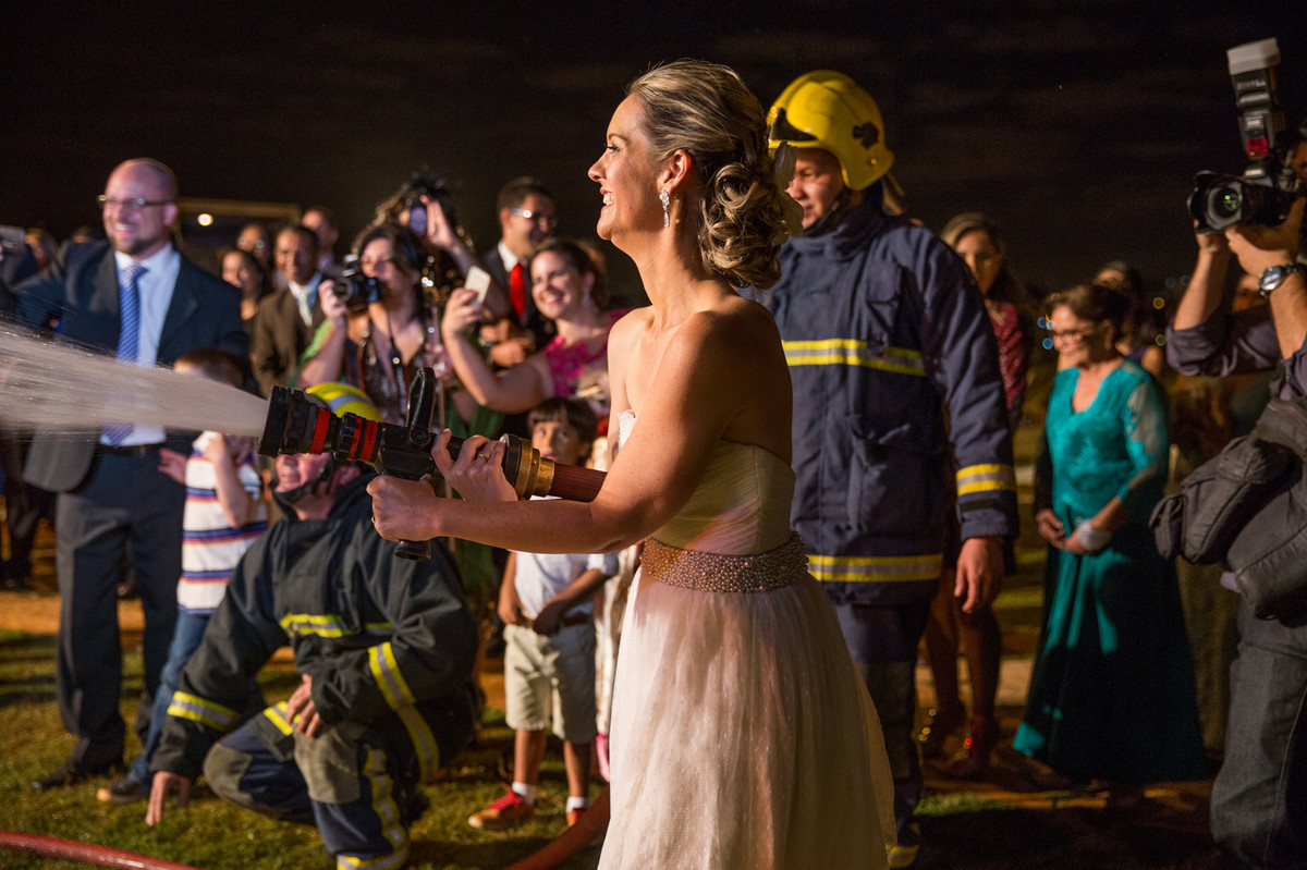Noiva dá banho de mangueira dos bombeiros no noivo na recepção do casamento