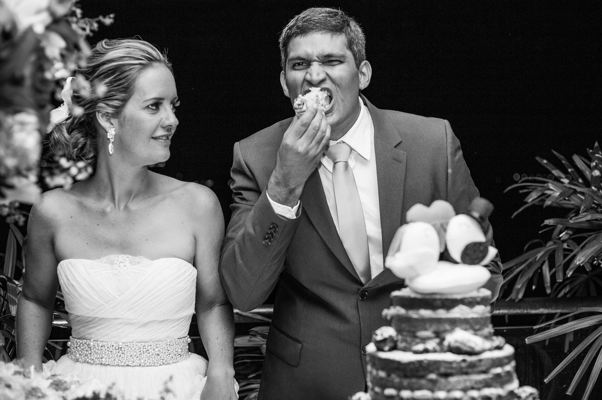 Noivo comendo pedaço do bolo na recepção do casamento