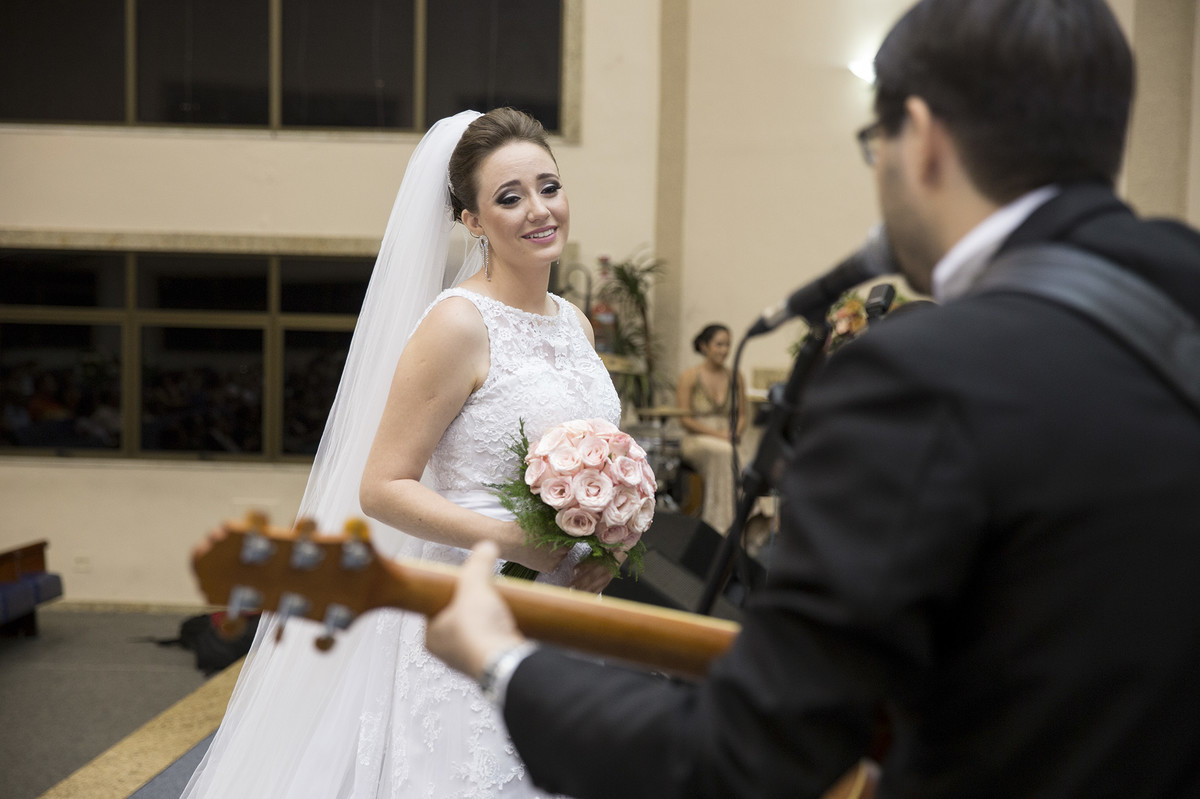 Noiva emocionada enquanto noivo toca violão e canta para ela na cerimônia