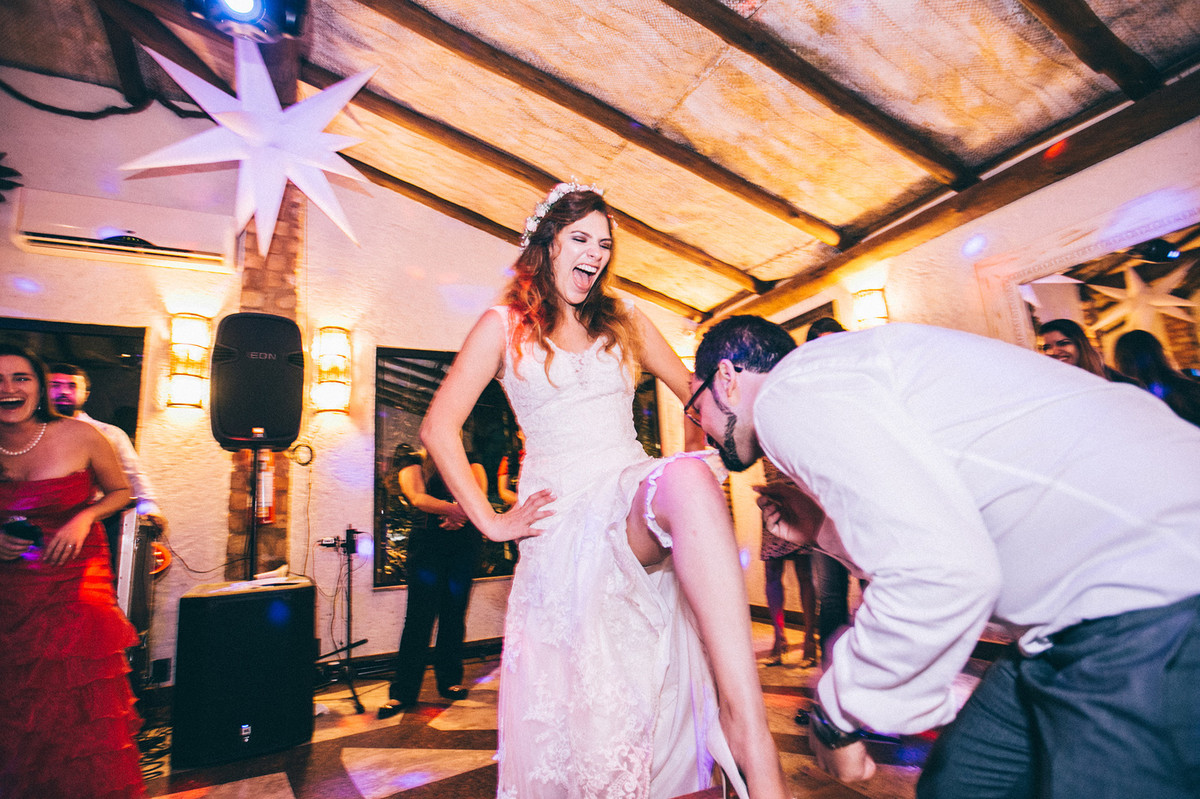 Casamento Aline e Gabriel Brasília - DF Noivo tirando a liga de perna da noiva com a boca para jogar