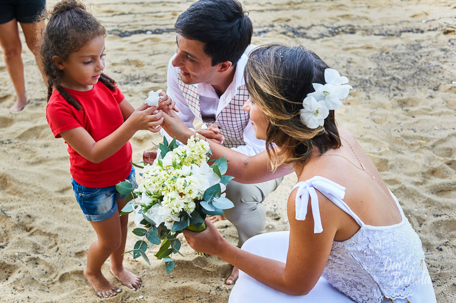 criança dando flor para noiva no casamento de dia ao ar livre na praia em paraty