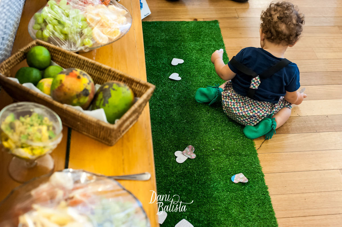 bebê brincando na mesa de frutas no aniversario infantil de 1 aninho
