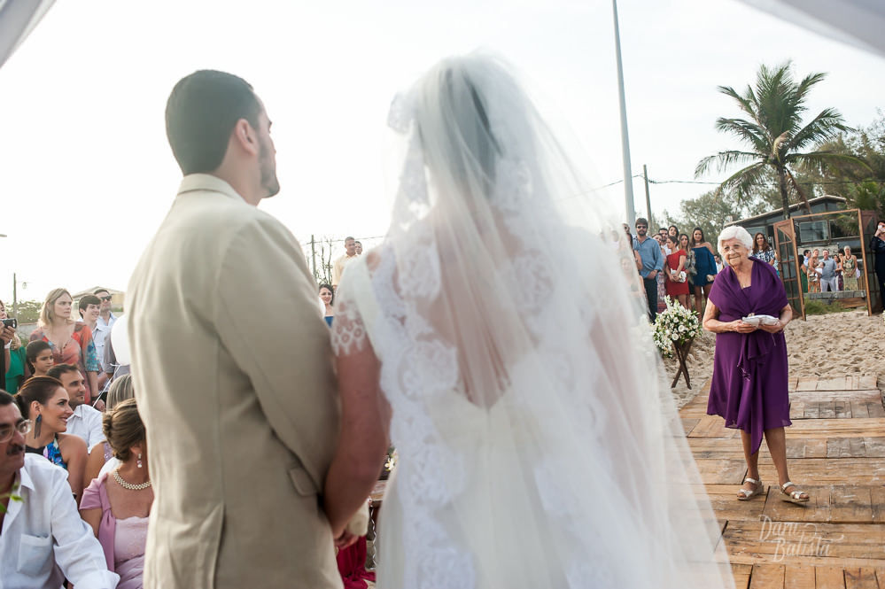 avó da noiva entrando com as alianças na cerimonia de casamento ao ar livre na praia do recreio