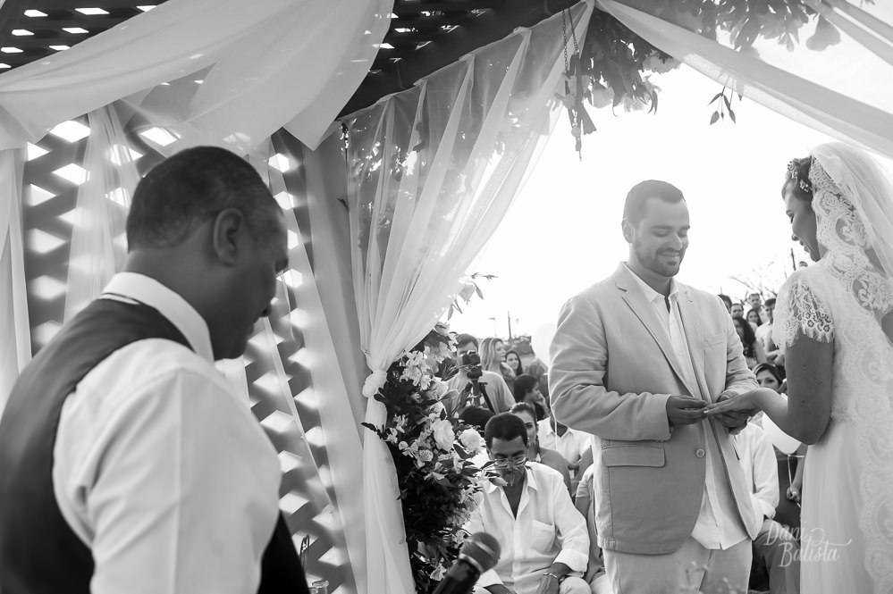 noivo colocando a aliança na noiva durante cerimonia de casamento ao ar livre na praia do recreio