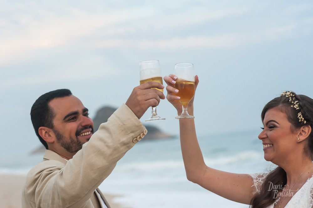 noivos brindando com cerveja na praia do recreio após cerimônia diurna de casamento