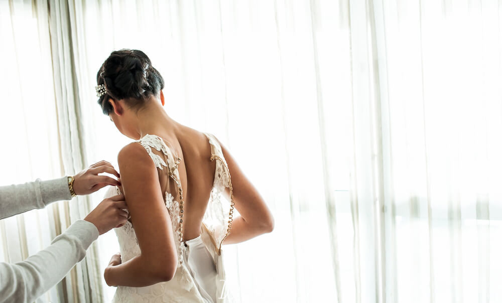 noiva colocando o vestido de noiva de renda da pronovias