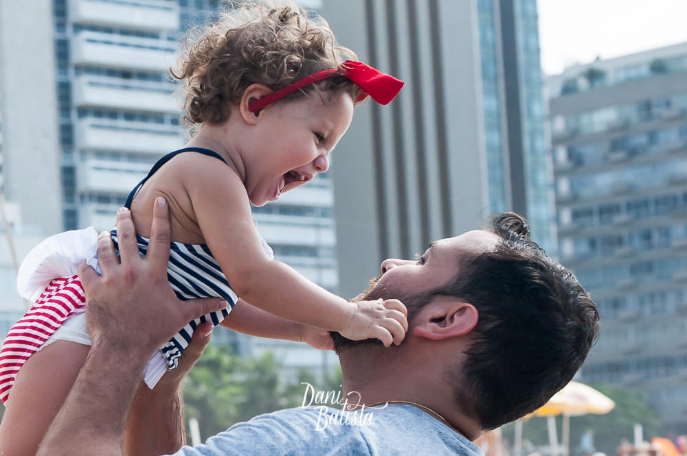 pai brincando com a filha durante ensaio fotografico de gestante na praia leblon