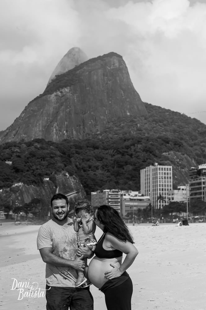 pais durante ensaio fotografico de gestante na praia leblon com o morro dois irmãos ao fundo