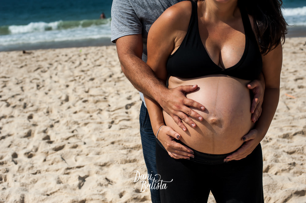 detalhe das mãos do casal na barriga durante ensaio fotografico de gestante na praia leblon