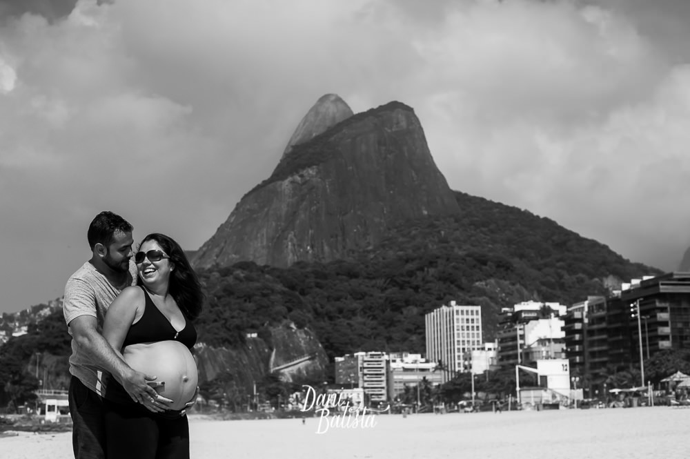 casal durante ensaio fotografico de gestante na praia leblon com o dois irmaos ao fundo